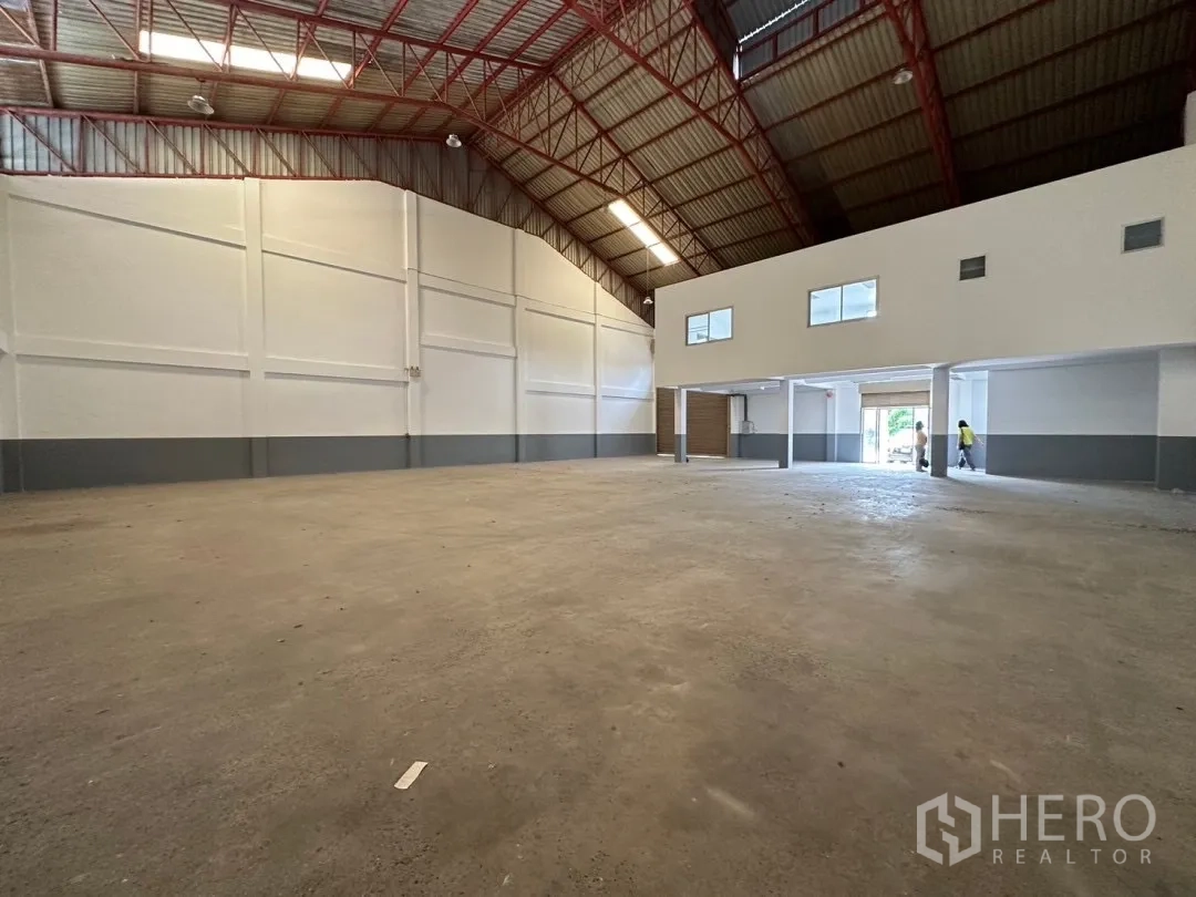 Factory for rent in Bang Sao Thong, Samut Prakan - Open production hall with high ceilings and a mezzanine office block at the entrance.