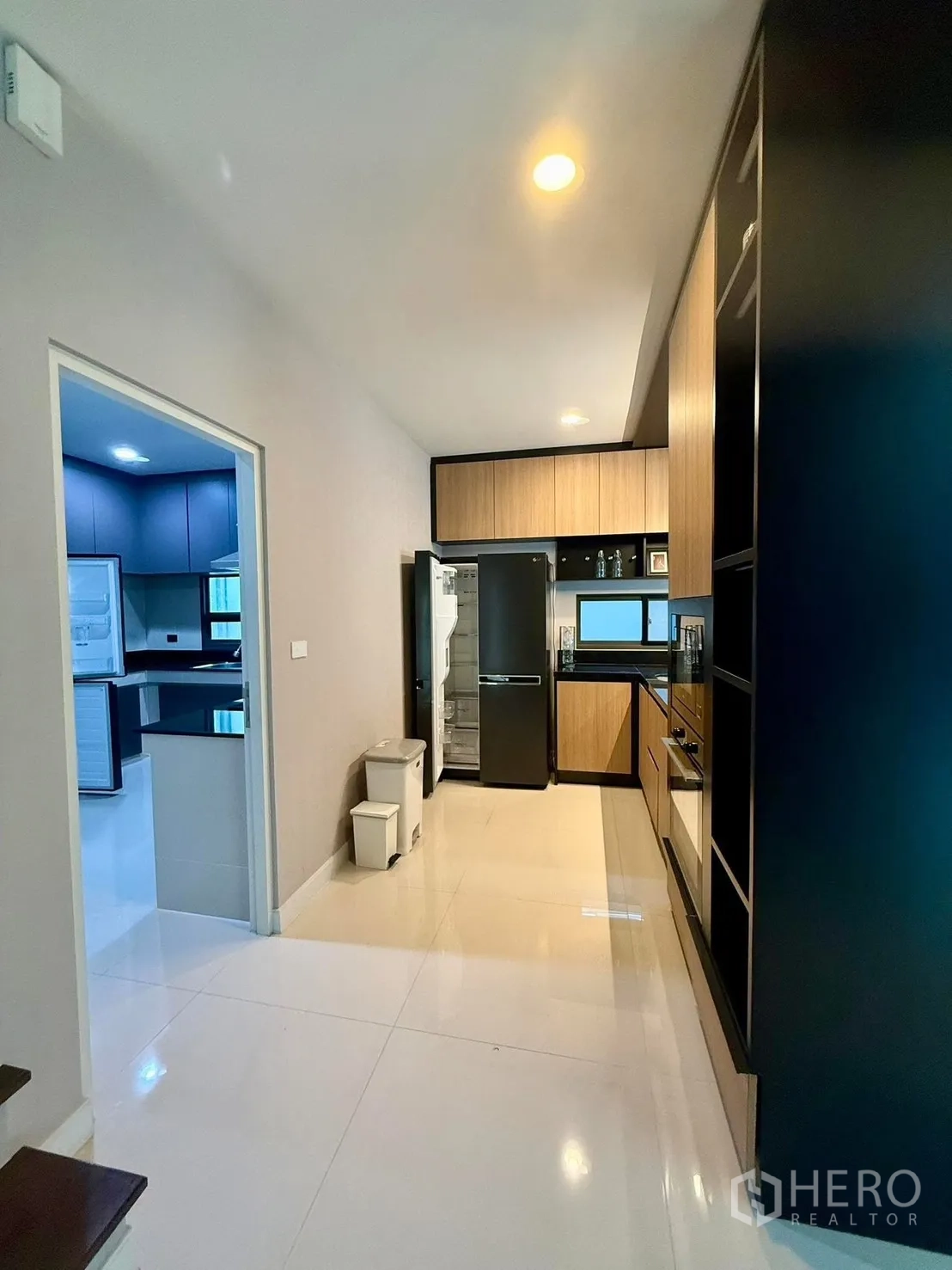 Detached House for rent in Bang Kapi, Bangkok - Pantry corridor leading to the kitchen with black fridge and ample cabinetry.