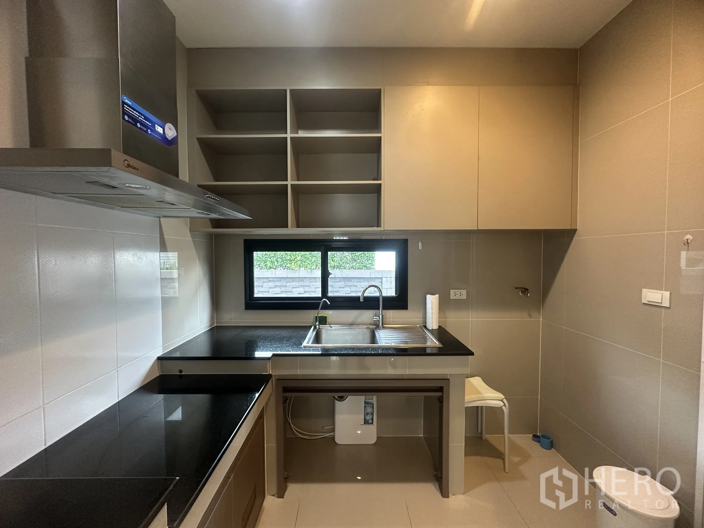 独栋房屋 for rent or sale in Lam Luk Ka, Pathum Thani - 设备齐全的厨房，黑色台面、水槽、橱柜与抽油烟机。