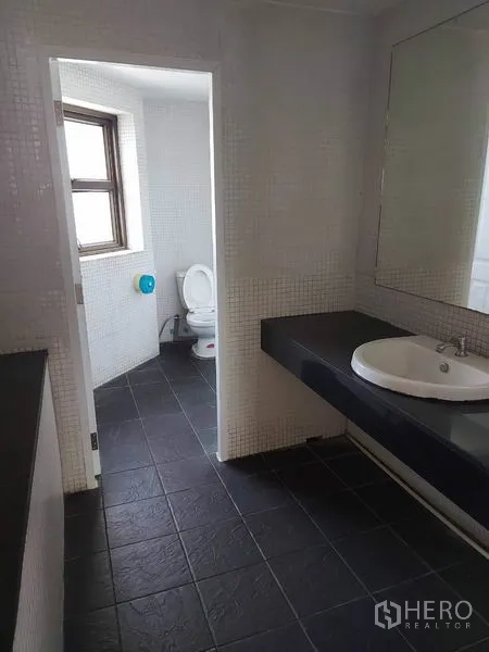 办公空间 出租在Pathum Wan, Bangkok - 现代化卫浴，超大镜面与黑色地砖，独立马桶间带窗。