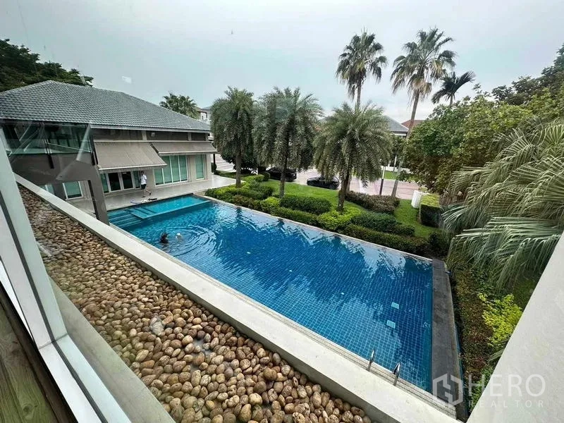 Detached House for sale in Saphan Sung, Bangkok - Large communal swimming pool bordered by palm trees and landscaped gardens.