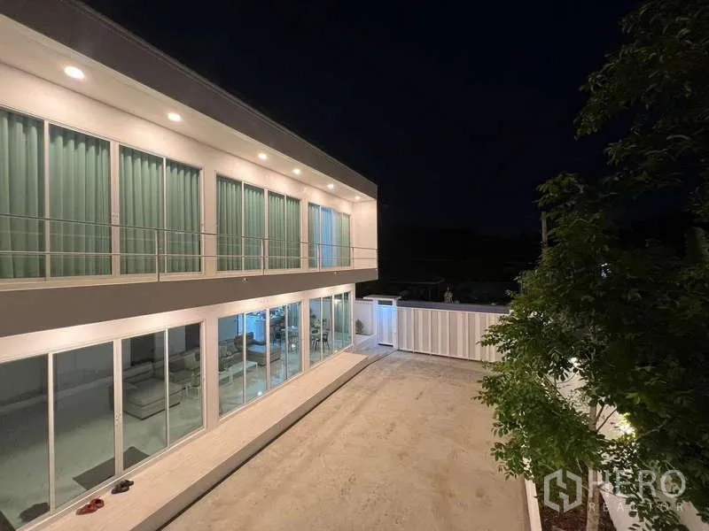 บ้าน ให้เช่าในLat Krabang, Bangkok - ลานบ้านและผนังกระจกของบ้านสองชั้น เปิดไฟสวยในยามค่ำ