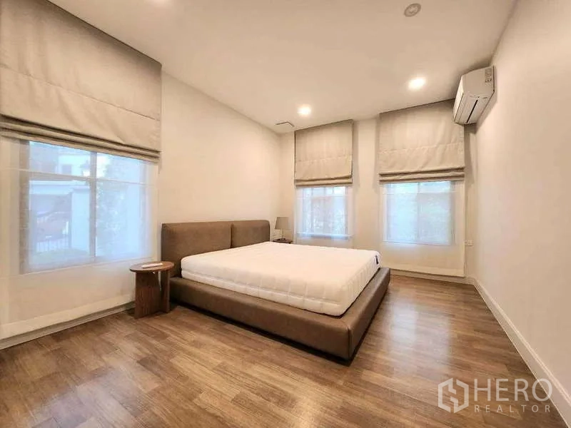 Detached House for rent in Saphan Sung, Bangkok - Cozy bedroom with upholstered bed, wood flooring, Roman blinds and soft lighting.