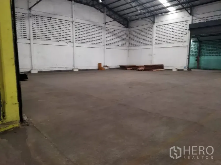Warehouse for rent in Khlong Sam Wa, Bangkok - Large warehouse interior with high metal roof, skylights, ventilated block walls and wide concrete floor.
