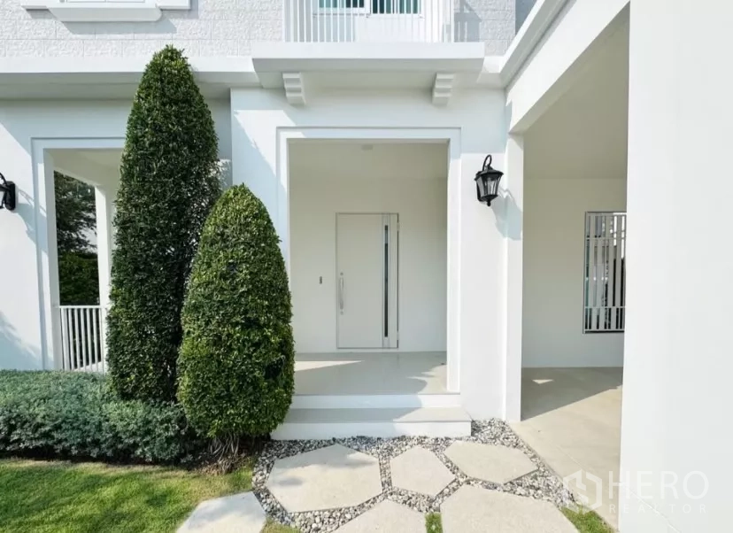 บ้าน ให้เช่าในBang Phli, Samut Prakan - เฉลียงทางเข้าพร้อมต้นไม้ตัดแต่ง โคมไฟติดผนัง และทางเดินแผ่นทางเท้า