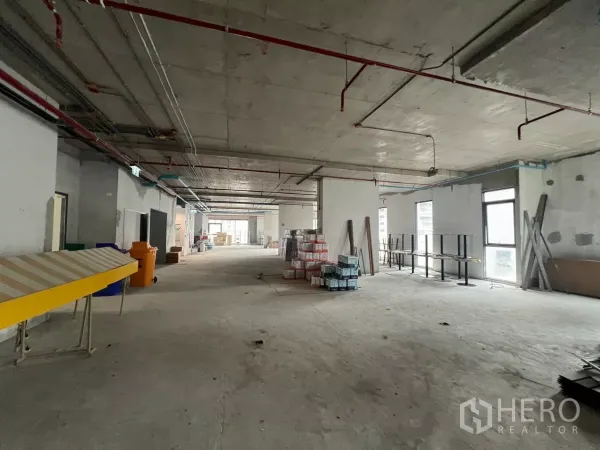 Office Space for rent in Khlong Toei, Bangkok - Long rectangular office floor plate with multiple windows and construction materials on site.