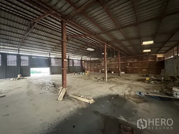 Warehouse for rent or sale in Yan Nawa, Bangkok - Wide interior of a steel-frame warehouse with high roof, concrete floor and roller shutters letting in daylight.