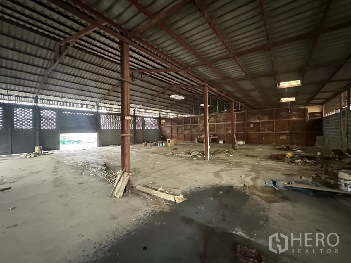 Warehouse for rent or sale in Yan Nawa, Bangkok - Wide interior of a steel-frame warehouse with high roof, concrete floor and roller shutters letting in daylight.