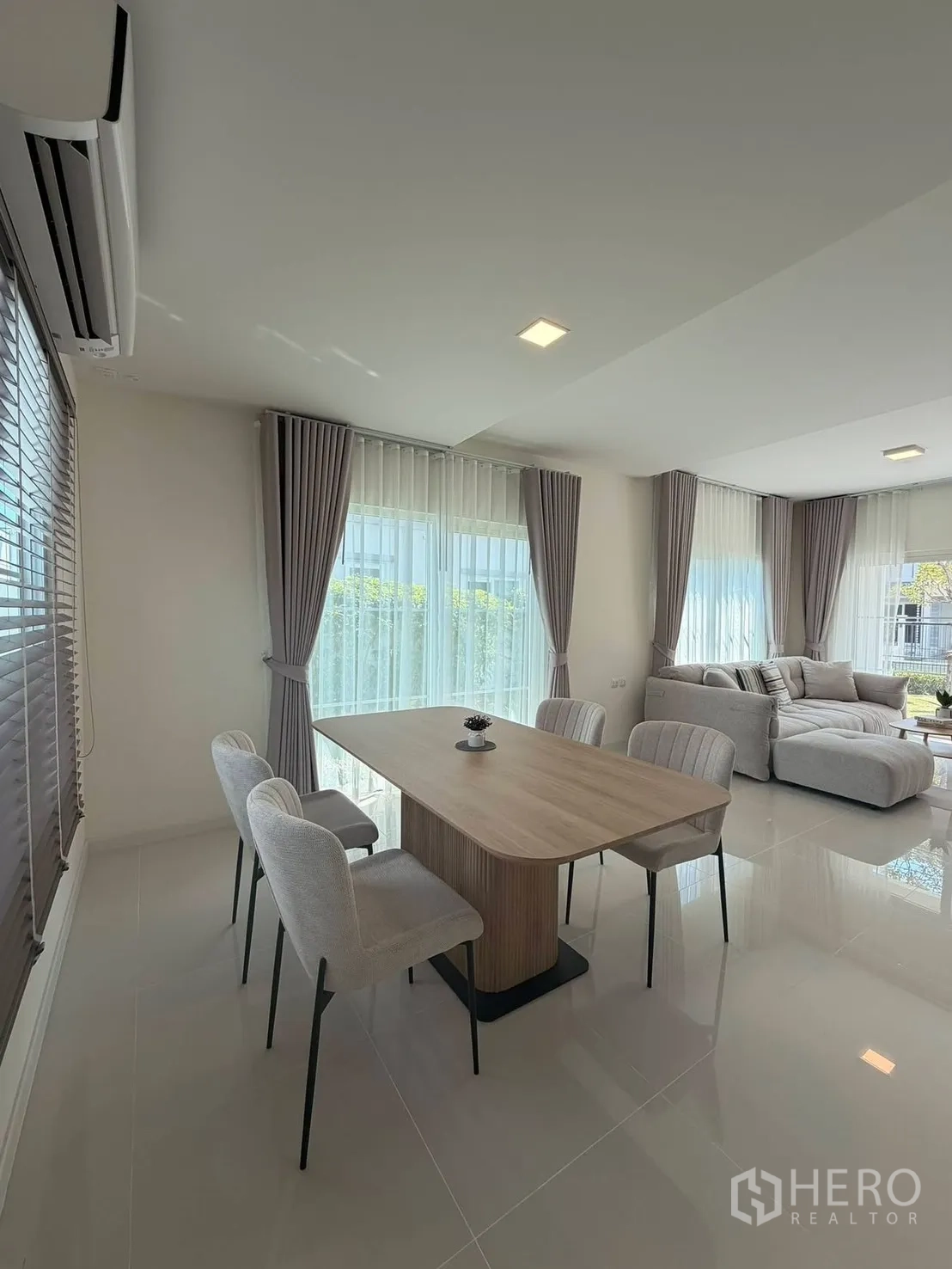 Detached House for rent in Bang Phli, Samut Prakan - Dining space with wooden table and four chairs beside floor-to-ceiling windows.