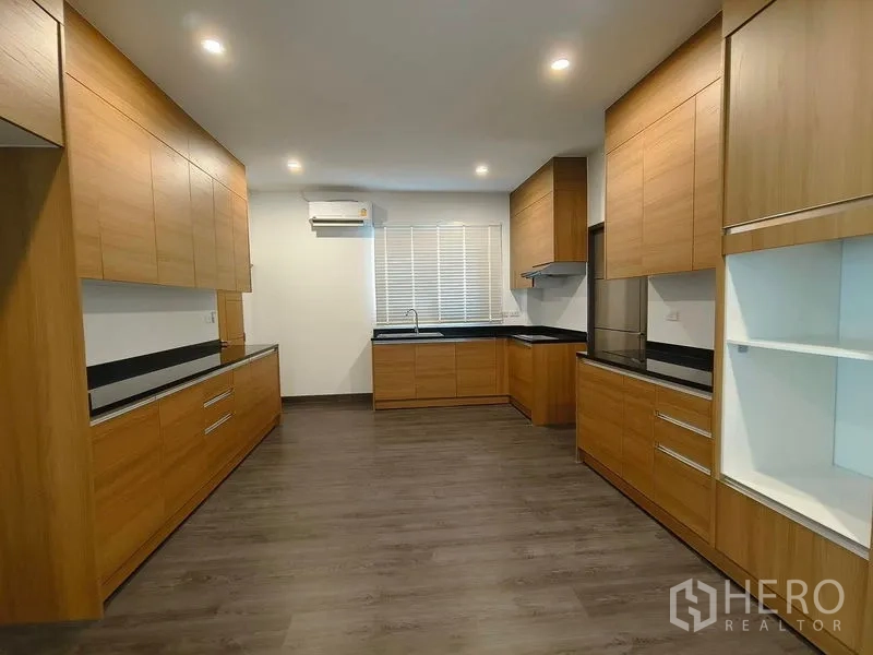 Detached House for rent or sale - Modern kitchen with extensive wood cabinetry, black stone countertops, and a window.