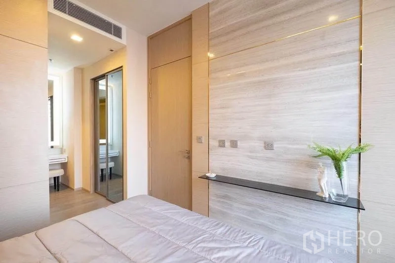 Condominium for rent in Watthana, Bangkok - Bedroom wall paneling with slim shelf, mirrored wardrobe and doorway to vanity and bath.