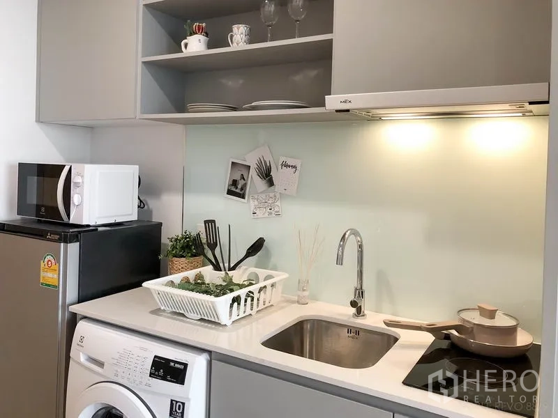 คอนโด ให้เช่าในBang Rak, Bangkok - ภาพระยะใกล้แพนทรีโทนเทาอ่อน พร้อมอ่างซิงก์ เตาปรุงอาหาร และที่เก็บของ.