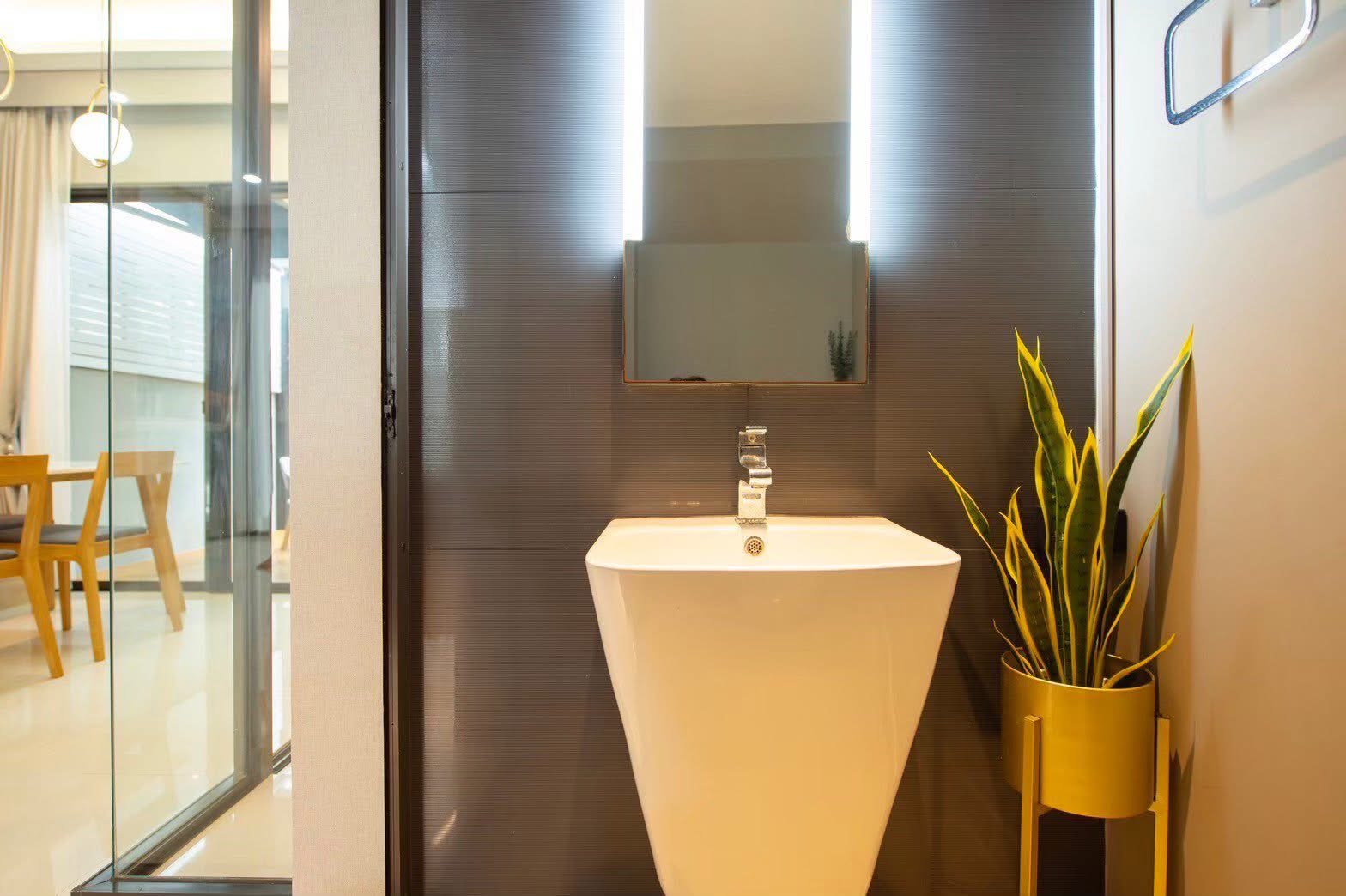 联排别墅 出租或出售在Lat Phrao, Bangkok - 卫浴带背光镜与现代立柱式洗手盆，旁设绿植。