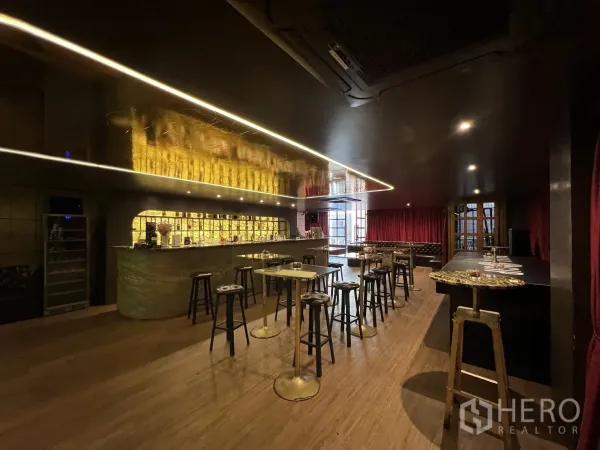 零售空间 出租在Watthana, Bangkok - 昏暗氛围的休闲区，带背光石材吧台、高脚桌和木地板