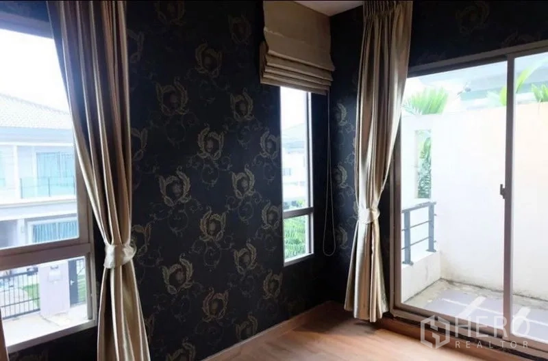 Detached House for rent in Suan Luang, Bangkok - Corner room with dark patterned wallpaper, tall windows, and sliding door to a small balcony.
