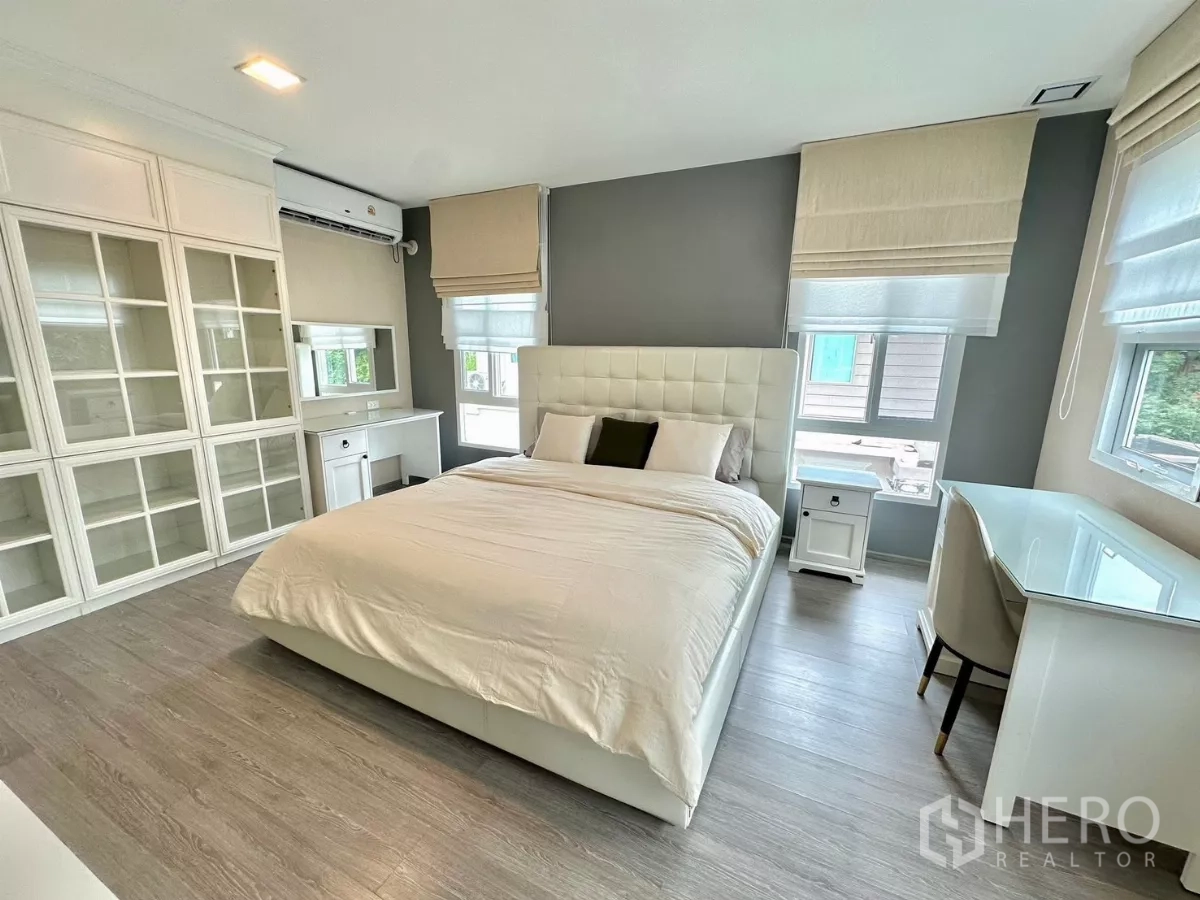 Detached House for rent in Bang Phli, Samut Prakan - Master bedroom with upholstered bed, built-in glass-door cabinets and study desk.
