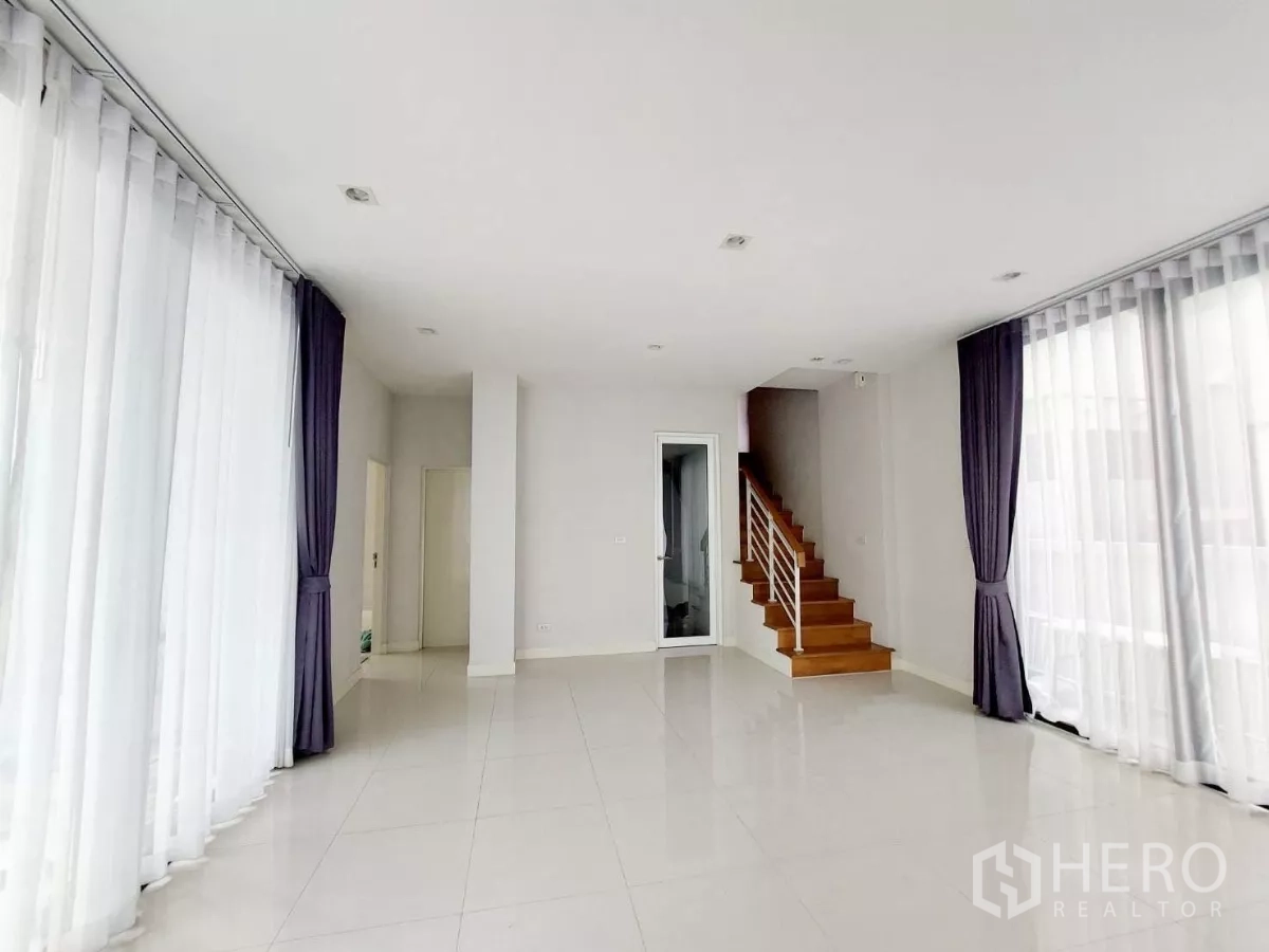 ทาวน์เฮาส์ ให้เช่าในLat Phrao, Bangkok - ห้องนั่งเล่นชั้นล่างสว่าง ด้วยประตูกระจกบานเลื่อนหลายด้านและบันไดขึ้นชั้นบน