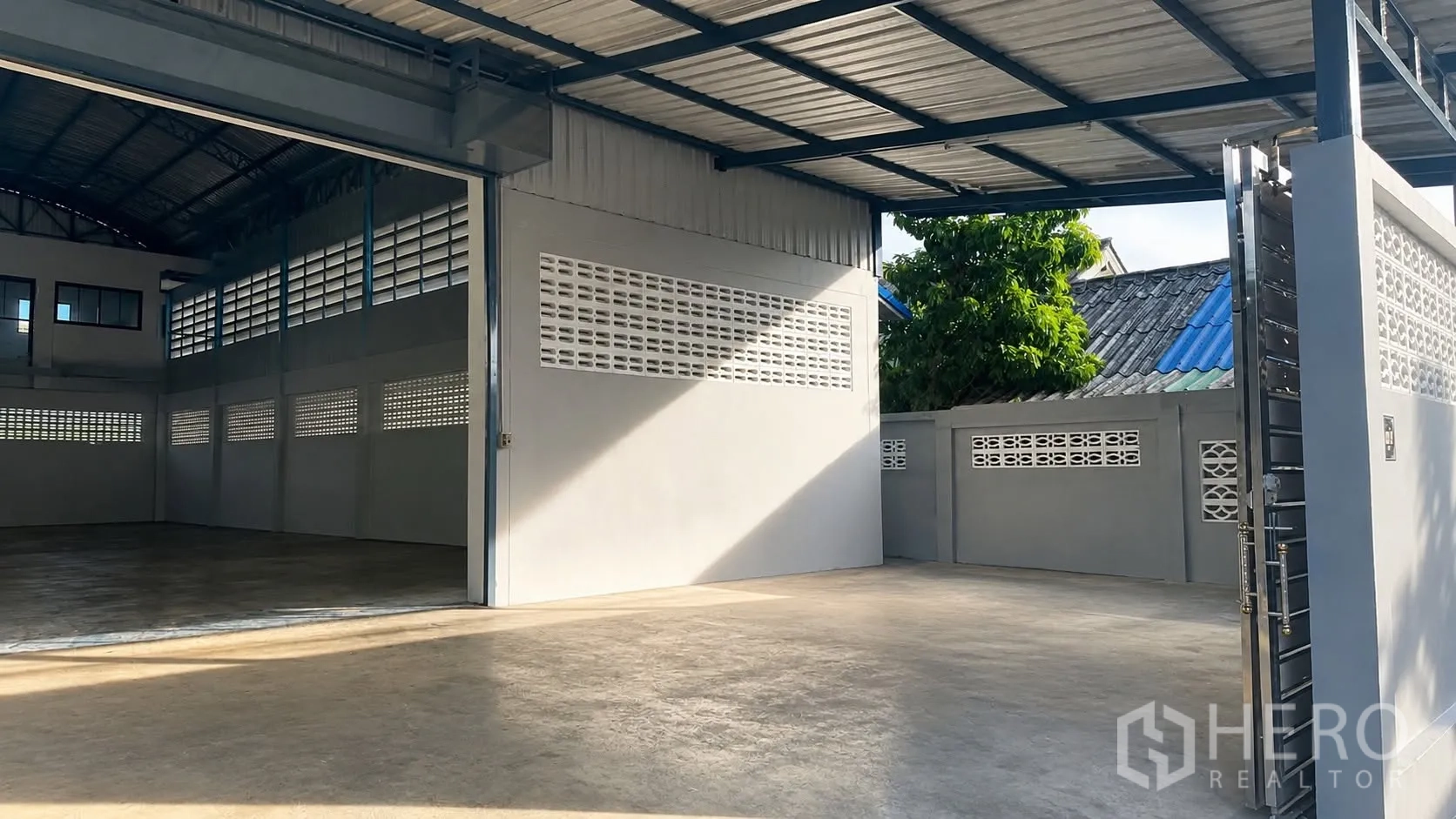Warehouse for rent in Mueang Samut Prakan, Samut Prakan - Covered loading area and open entrance to a clear-span warehouse with a concrete floor.