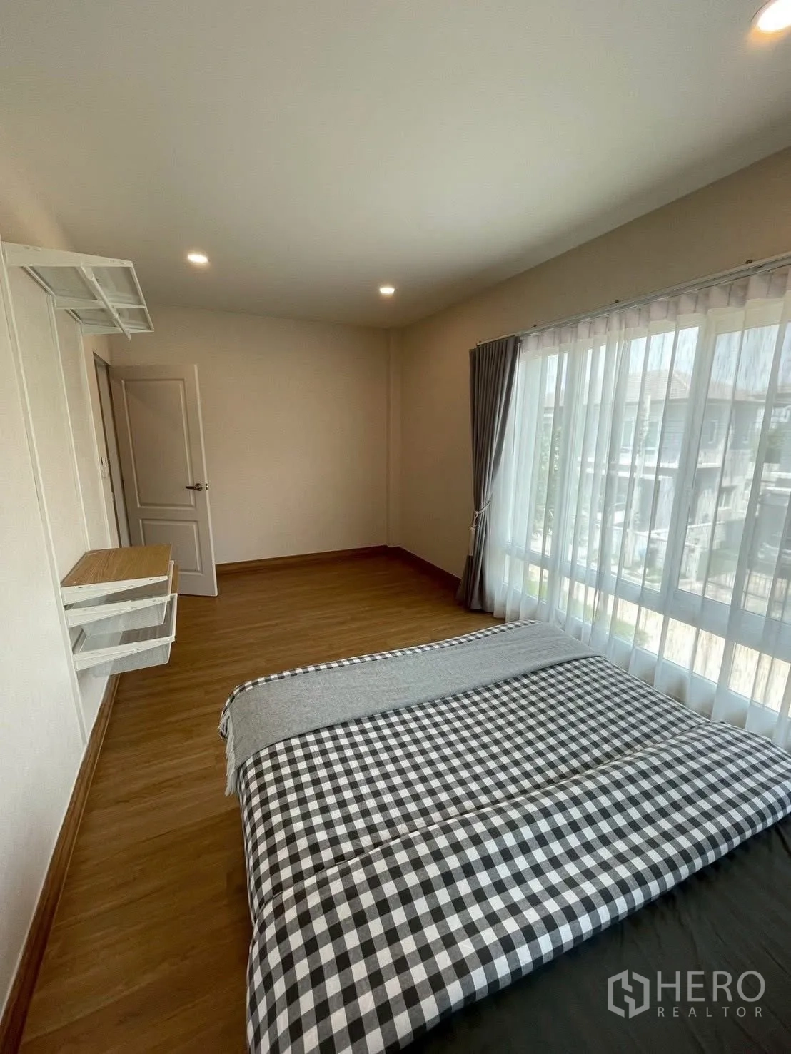 Detached House for rent in Prawet, Bangkok - Bright bedroom with checkered bedding and a wide window wall.