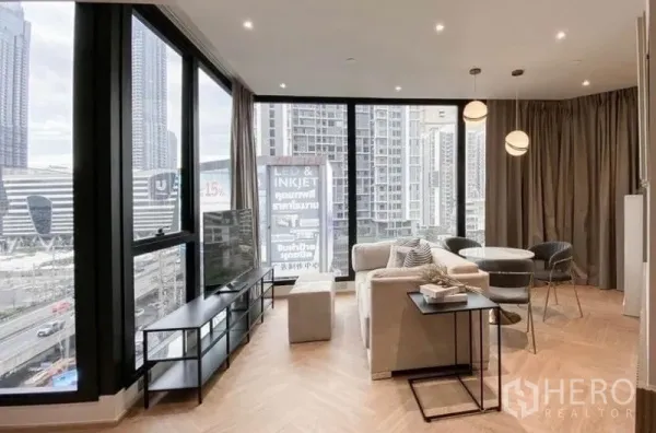 Condominium for rent in Din Daeng, Bangkok - Bright corner living room with floor-to-ceiling windows, herringbone wood floors and a city skyline view.