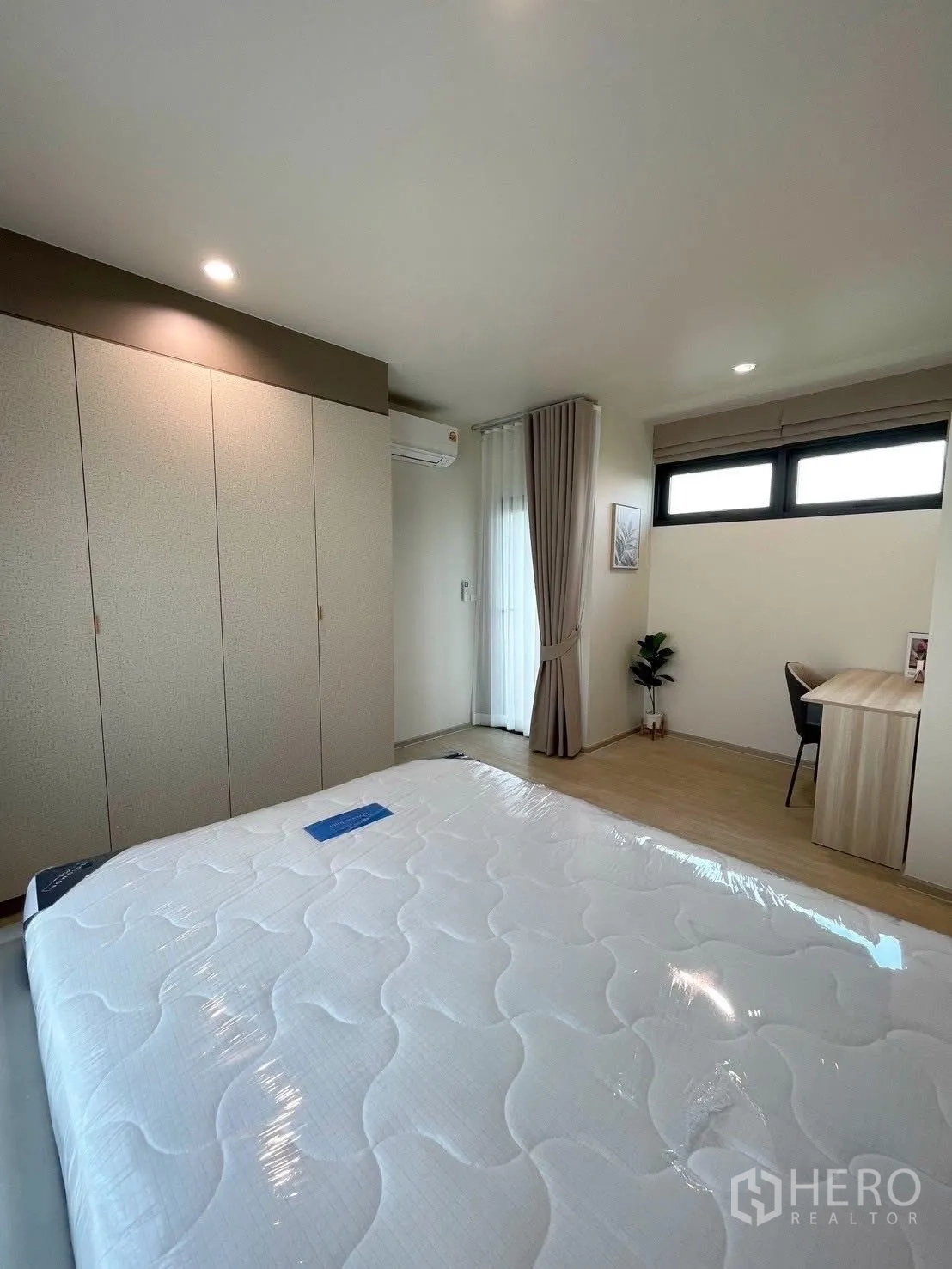 Detached House for rent in Bang Phli, Samut Prakan - Primary bedroom featuring wall-length wardrobe, upholstered bed, air conditioning and study area.