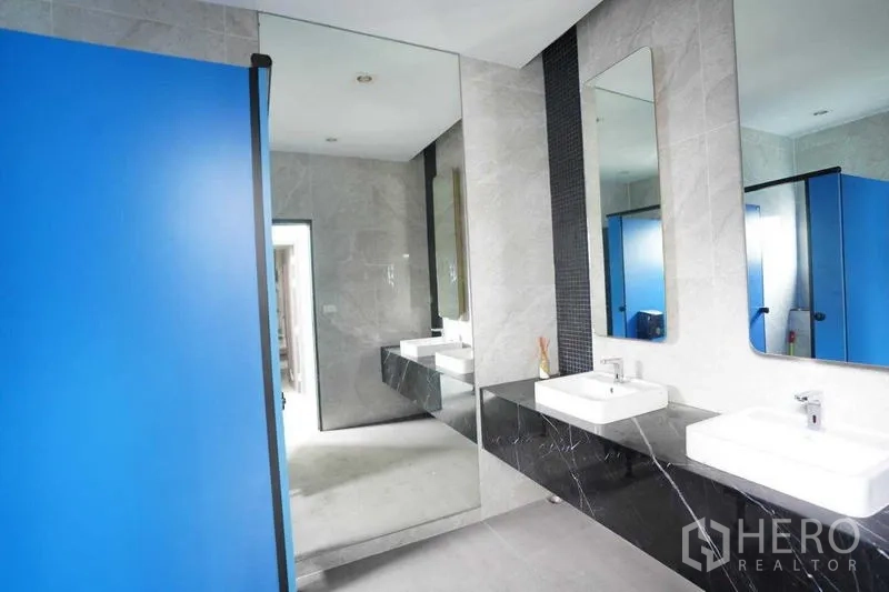 独立商业地产 出租在Bang Na, Bangkok - 现代化洗手间，双台盆、大镜面与蓝色隔间。