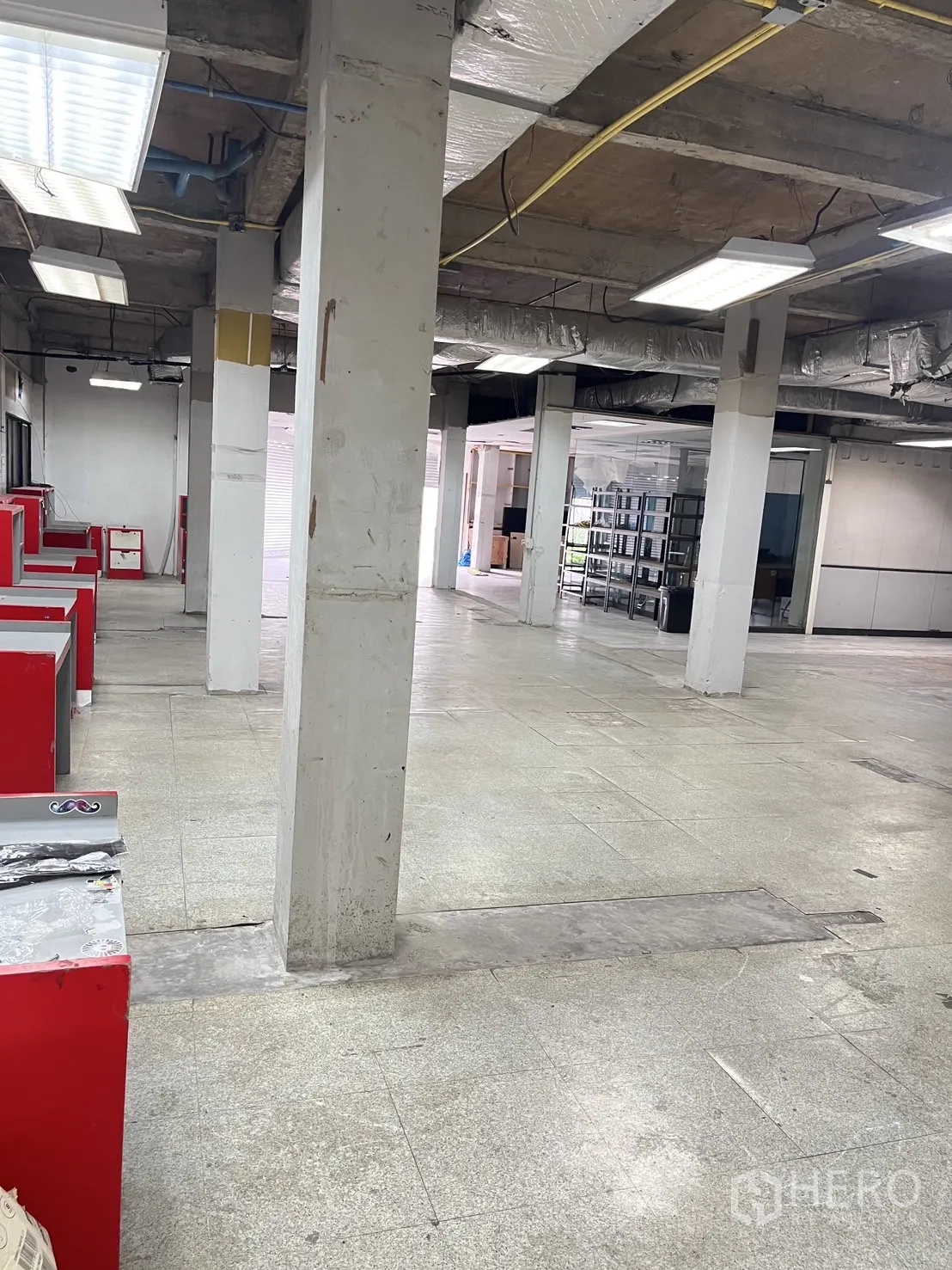 Warehouse for rent in Huai Khwang, Bangkok - Large open warehouse floor with concrete columns, fluorescent lighting and nearby loading bays.