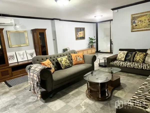 联排别墅 出租在Prawet, Bangkok - 客厅配两张沙发、玻璃茶几与木质电视柜。