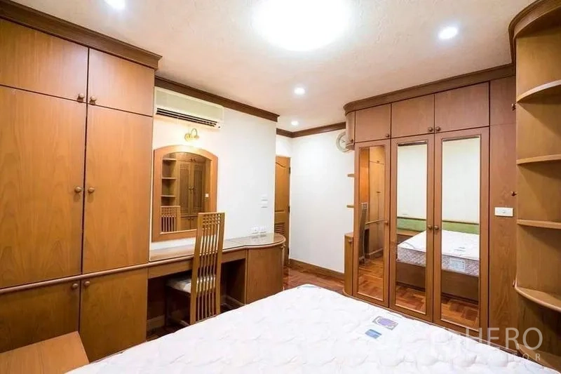 公寓 出租或出售在Bang Phlat, Bangkok - 卧室配木质整体衣柜与镜面门，书桌与人字拼木地板。