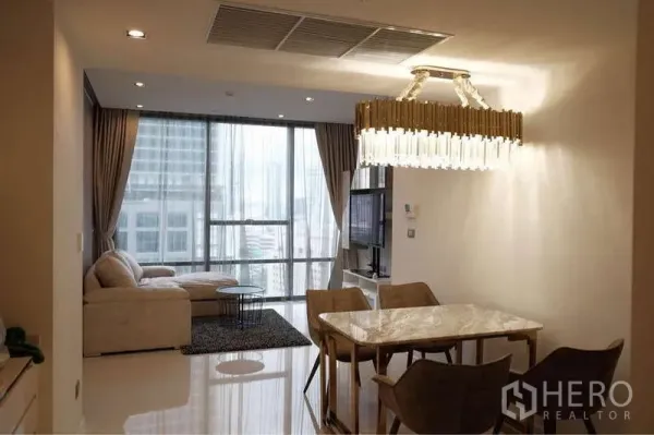 Condominium for rent in Sathon, Bangkok - Open-plan living and dining room with marble table, chandelier and floor-to-ceiling windows overlooking Bangkok.