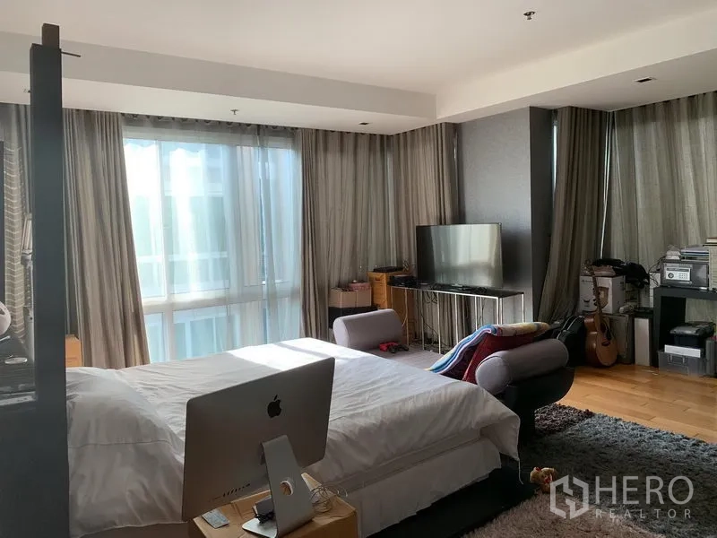 คอนโด ขายในKhlong Toei, Bangkok - มุมห้องนอนเห็นหน้าต่างมุม โซฟานั่งเล่น และตู้วางทีวี