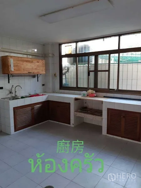 Townhouse for rent in Watthana, Bangkok - Spacious kitchen with L‑shaped counters, tiled walls and large window.