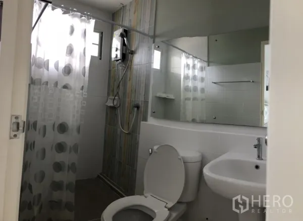 Townhouse for rent in Bang Bo, Samut Prakan - Bathroom with shower area, water heater, polka-dot curtain, toilet and sink.