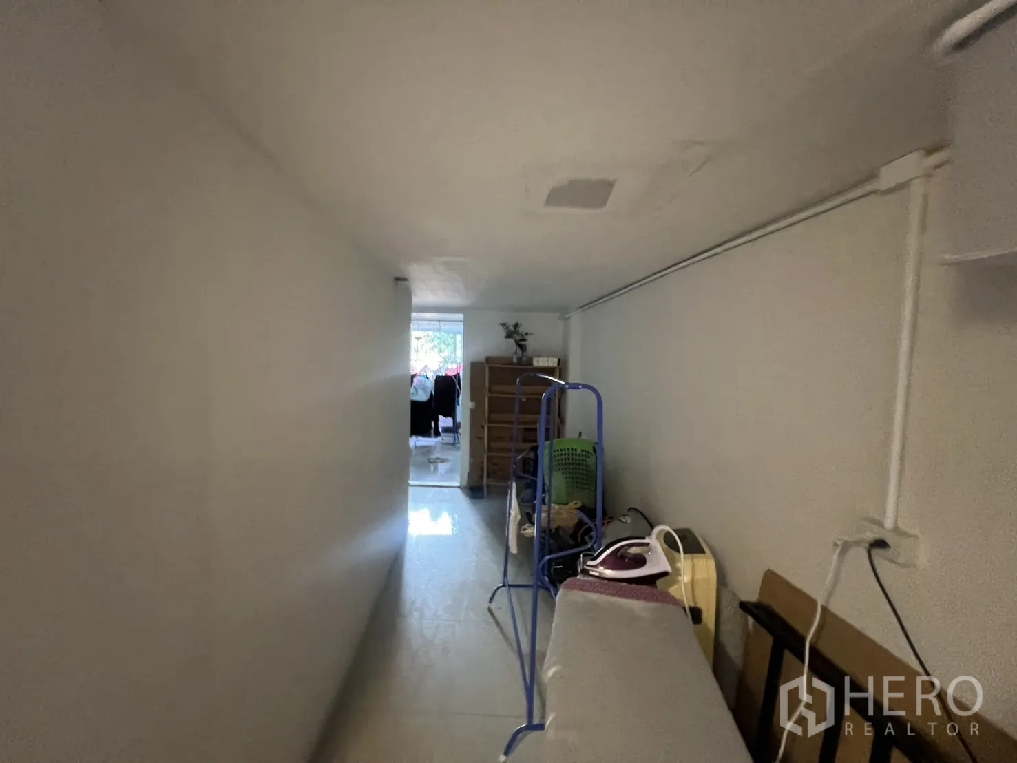 พื้นที่ขายปลีก ให้เช่า - มองตามทางเดินไปยังห้องปลายทางที่มีหน้าต่าง มีโต๊ะรีดผ้าและพื้นที่เก็บของข้างผนัง