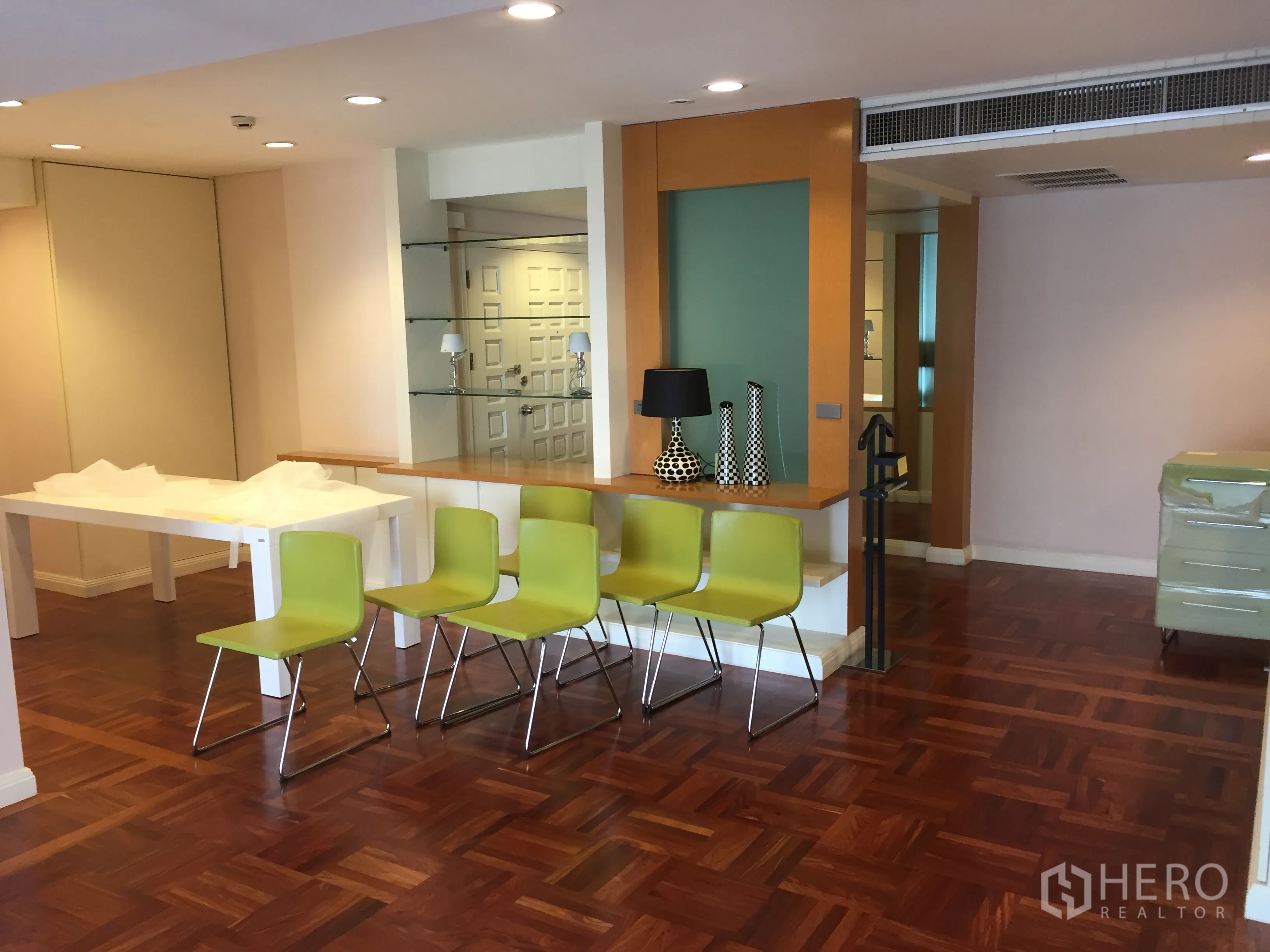 Condominium for rent in Pathum Wan, Bangkok - Open-plan living and dining area with parquet floors, breakfast bar and recessed lighting.