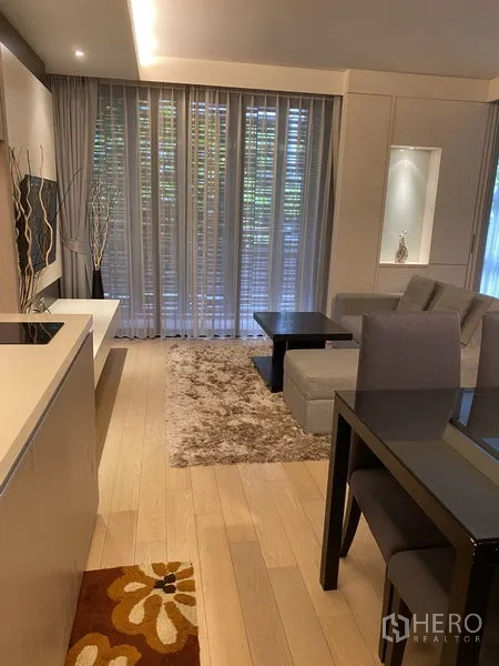 Condominium for rent in Watthana, Bangkok - Open‑plan kitchen and living space with light wood floors, coffee tables, and expansive windows.