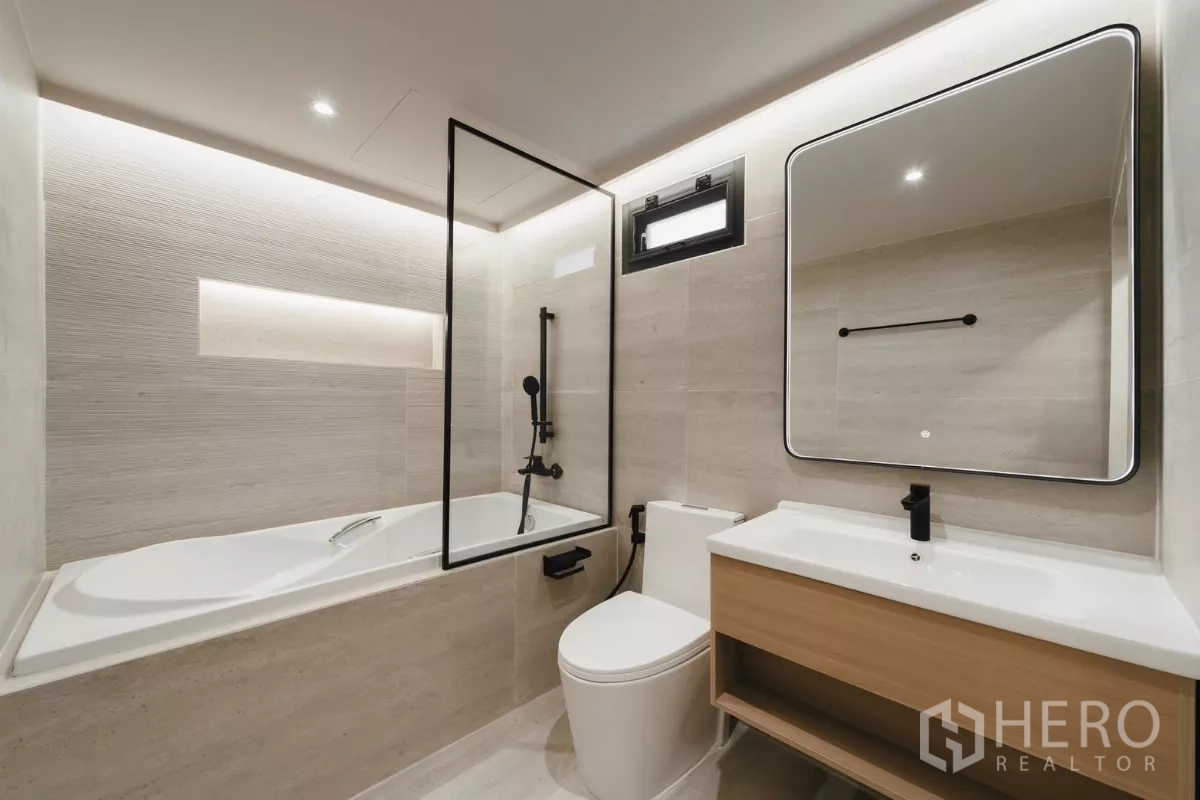 联排别墅 出租在Watthana, Bangkok - 现代浴室，浴缸、玻璃隔断、洗手台与背光镜。