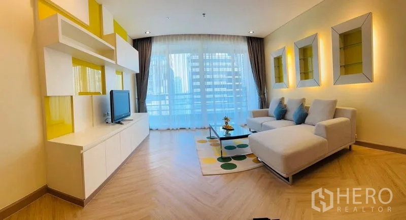 公寓 出租在Bang Rak, Bangkok - 明亮客厅，转角沙发、电视柜、人字拼木地板，落地窗连通城市景观阳台。