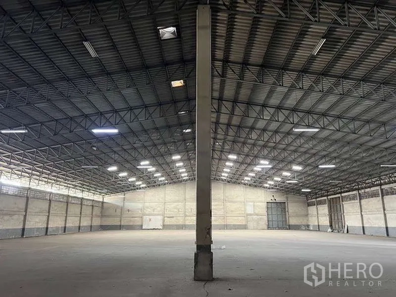 Warehouse for rent - Symmetrical view of the warehouse with a central column and large loading doors at the far end.