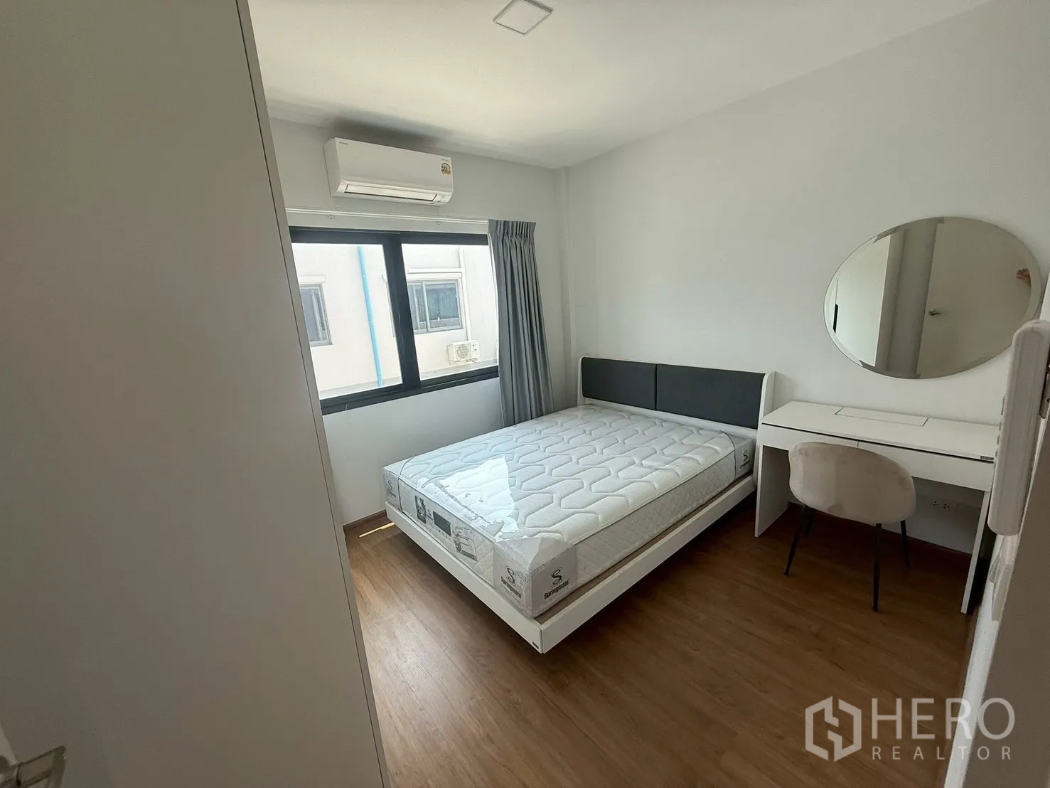 Townhouse for rent in Bang Phli, Samut Prakan - Bedroom with desk, round mirror, bed and window AC.