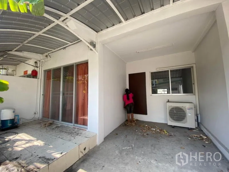 联排别墅 出租在Watthana, Bangkok - 带金属顶棚的有盖车位/庭院，推拉门与室外空调机组。