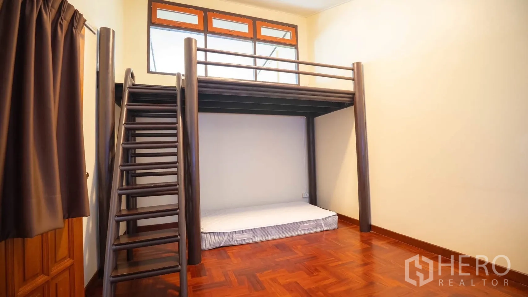 Townhouse for rent in Watthana, Bangkok - Room with raised loft bed platform and ladder, wood floors, and a high window.