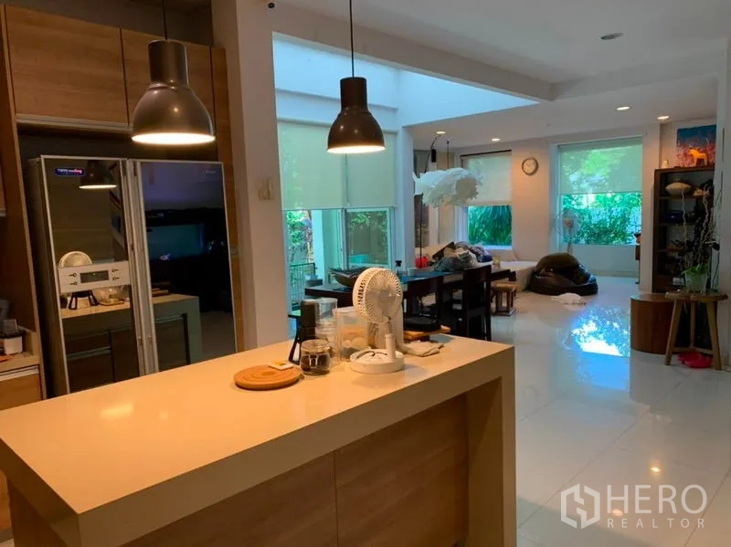 บ้าน ขายในSuan Luang, Bangkok - มุมมองจากไอส์แลนด์ครัวสู่โซนกินข้าวและนั่งเล่น พร้อมโคมไฟแขวนและหน้าต่างบานใหญ่หันสู่สวน