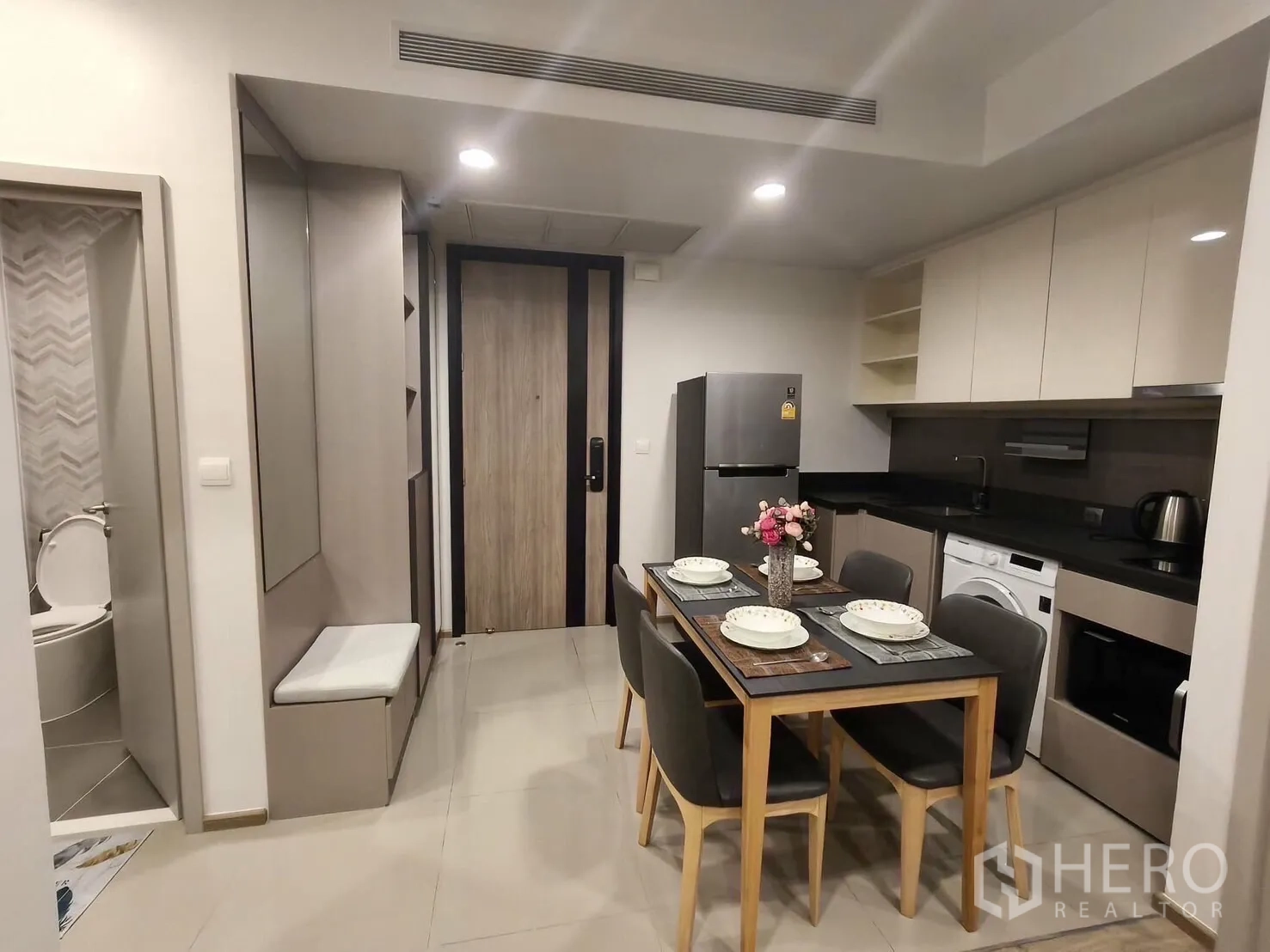 คอนโด for rent in Khlong Toei, Bangkok - โถงทางเข้าและครัวสมัยใหม่ พร้อมโต๊ะอาหาร 4 ที่นั่ง ตู้เย็น และเห็นห้องน้ำลายก้างปลา
