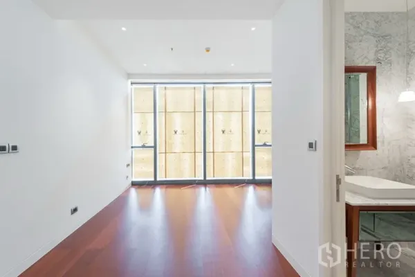 คอนโด ขายในWatthana, Bangkok - มุมมองห้องนอนไปยังหน้าต่างสูง พร้อมห้องน้ำหินอ่อนและตู้ฝักบัวกระจกที่เชื่อมต่อ