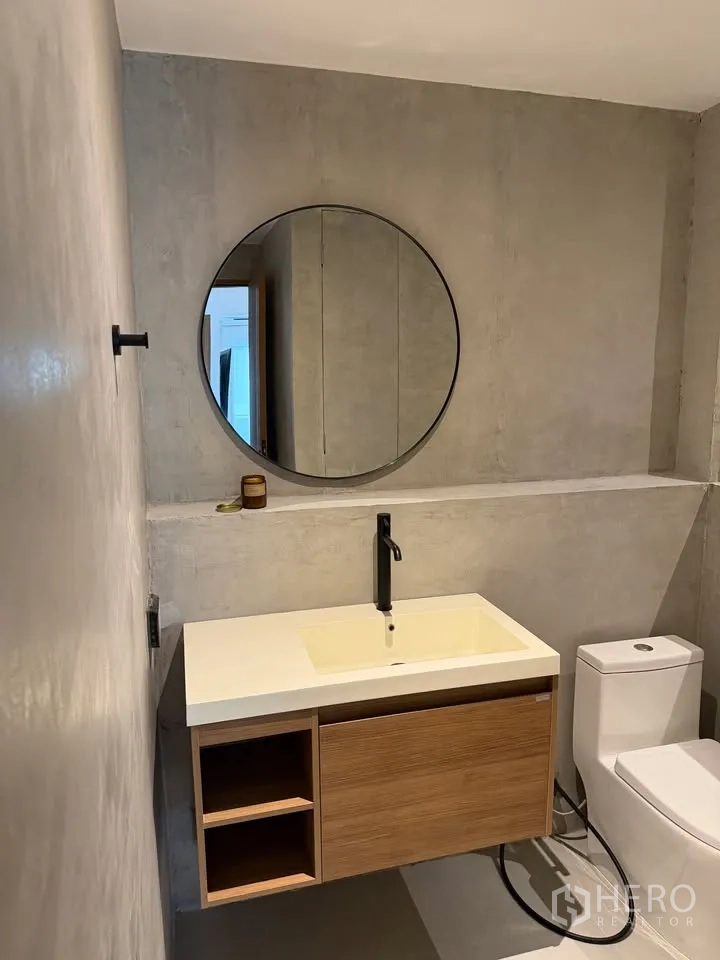 Condominium for rent in Watthana, Bangkok - Bathroom with round mirror, floating vanity, and toilet.