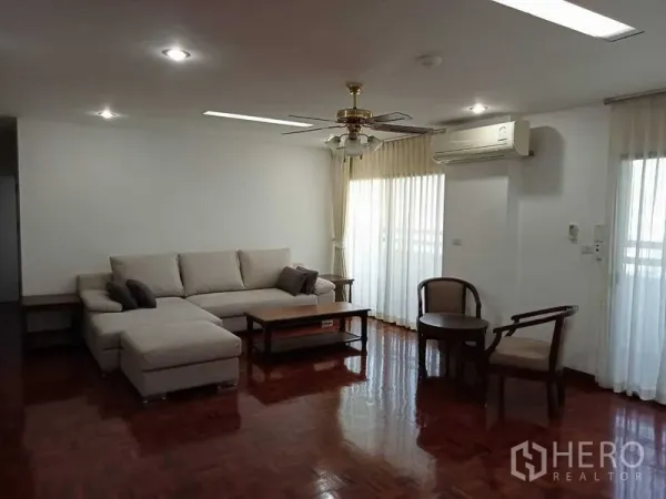 Condominium for rent in Watthana, Bangkok - Living room angle with sectional sofa, coffee table, ceiling fan and air conditioner.