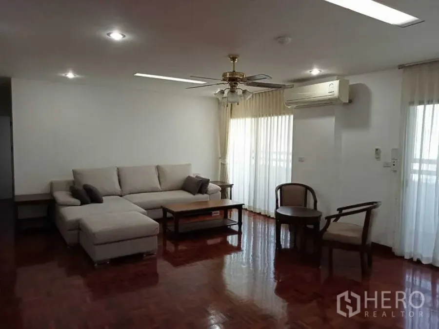 Condominium for rent in Watthana, Bangkok - Living room angle with sectional sofa, coffee table, ceiling fan and air conditioner.