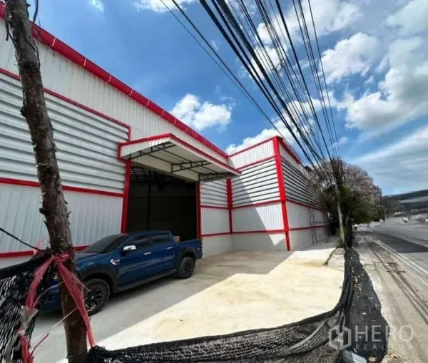 货栈 出租在Sai Mai, Bangkok - 临街现代仓库外观，红色边框金属板，带大型卷门与雨棚装卸区。