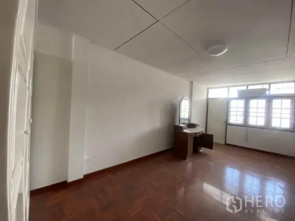 联排别墅 出租在Watthana, Bangkok - 采光良好的卧室，大片格窗、木地板和木质梳妆台。